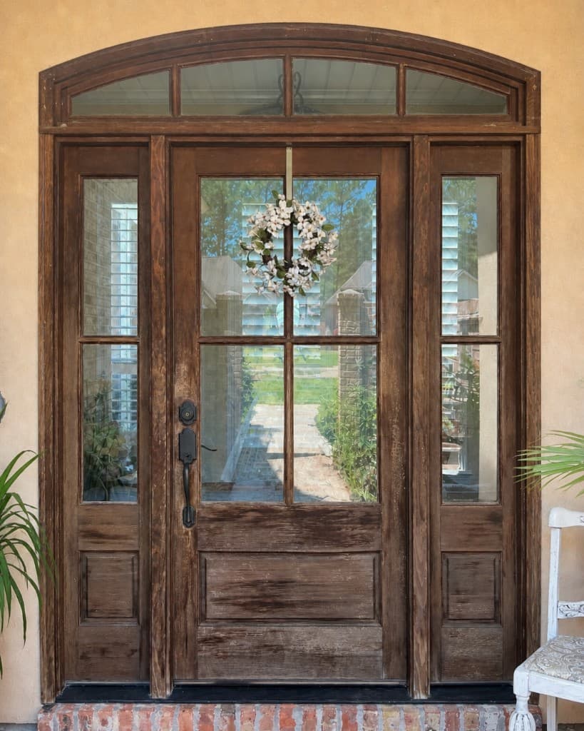 Before: weathered wood front door in Mandeville LA showing faded finish and exposed grain before refinishing